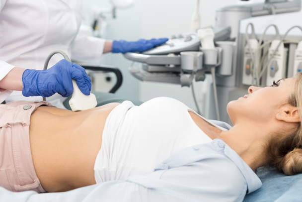 врач, осматривающий желудок красивого пациента с помощью ультразвукового сканирования в клинике
  - Фото, изображение