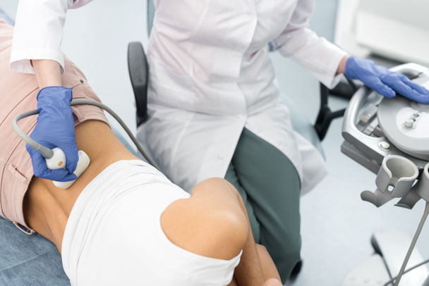 обрезанный вид врача, осматривающего почки пациента с помощью ультразвукового сканирования в клинике
 - Фото, изображение