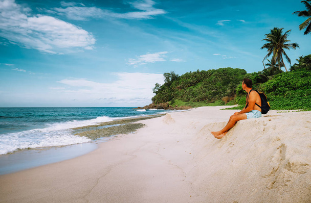 Male traveler sitting on sand enjoy tropical beach with ocean lagoon on vacation holidays - Fotografie, Obrázek