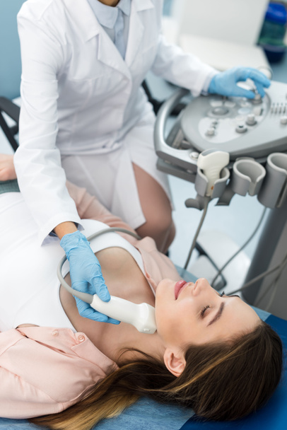 Medico che esamina la tiroide della paziente con ecografia in clinica - Foto, immagini