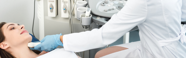 panorámás felvétel a klinikán ultrahangos vizsgálaton átesett nőbetegek pajzsmirigyét vizsgáló orvosról - Fotó, kép