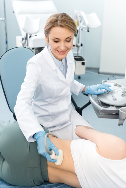 médico sorridente profissional examinando rim de paciente feminino com ultra-som na clínica
   - Foto, Imagem