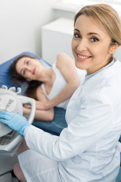 診療所で超音波検査を受けた女性患者の腎臓を調べる笑顔の医者   - 写真・画像