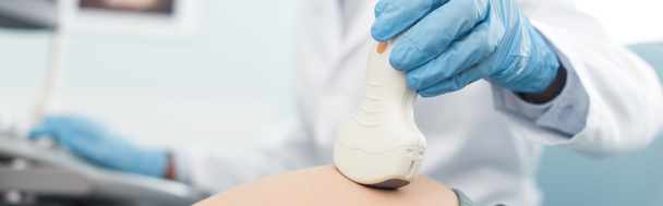 tiro panorâmico do médico examinando a barriga da mulher grávida com ultra-som na clínica
 - Foto, Imagem