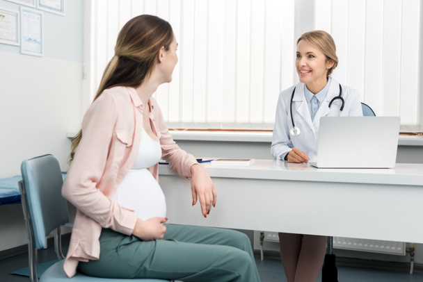νεαρή έγκυος γυναίκα που έχει συμβουλευτεί γιατρό σε γυναικολογική κλινική - Φωτογραφία, εικόνα
