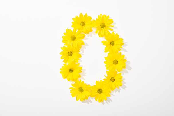 top view of yellow daisies arranged in number 0 on white background - Photo, Image