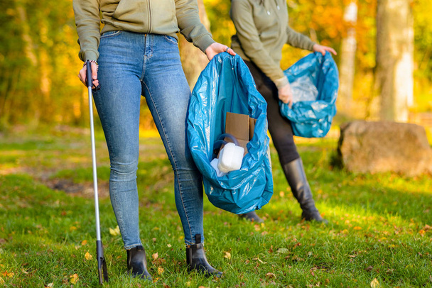 Vapaaehtoiset naiset keräävät roskia nurmikolta - Valokuva, kuva
