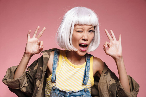 Image of positive asian girl making face and showing okey sign - Фото, изображение