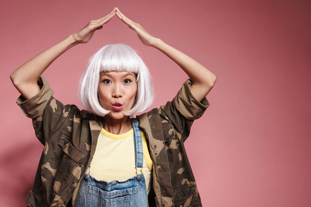 Image of asian girl in white wig making roof above her head with - Photo, image