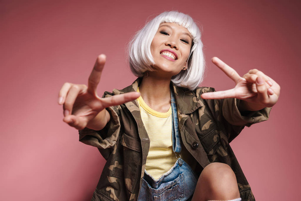 Image of asian girl wearing white wig smiling and gesturing peac - Valokuva, kuva