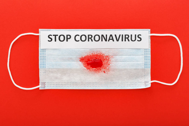 Stop coronavirus text on protective surgical masks with blood, hemoptysis on red background.Chinese Coronavirus, wuhan virus,Coronavirus outbreak, coronaviruses influenza.Stop coronavirus warning sign - Фото, зображення