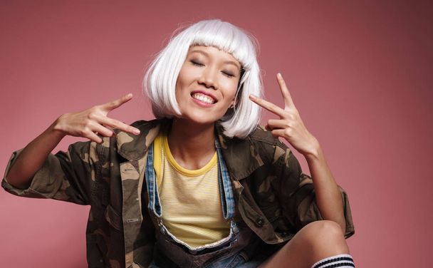 Image of asian girl wearing white wig smiling and gesturing peac - Valokuva, kuva