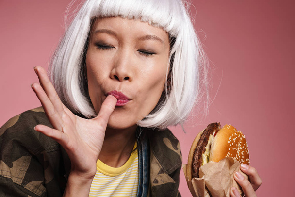Image of young asian girl in white wig having fun and eating big - Foto, Bild