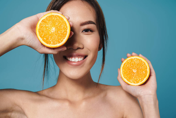 Portrait of half-naked asian woman holding orange and smiling - Фото, зображення