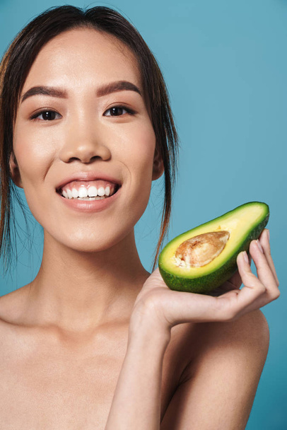 Portrait of half-naked asian woman holding avocado and smiling - Фото, зображення