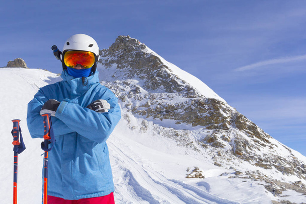 Skier άνθρωπος με πορτοκαλί γυαλιά σκι σε λευκό κράνος κάνουν φωτογράφηση στην κορυφή των Άλπεων βουνά. Στο φόντο των βουνών. Κλείσιμο προβολής. - Φωτογραφία, εικόνα