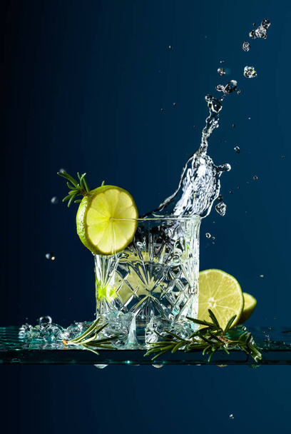 Cocktail gin-tonic limellä ja rosmariinilla lasipöydällä
. - Valokuva, kuva