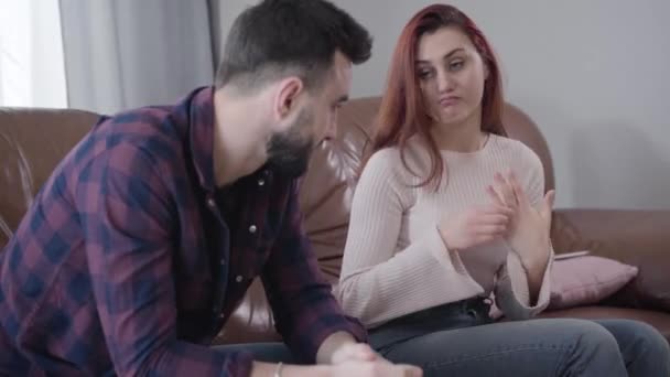 Annoyed young Caucasian woman putting wedding ring into mans hand and turning away. Depressed handsome man rubbing face at the foreground. Divorce, breakup, marriage problems. Focused at background. - Séquence, vidéo