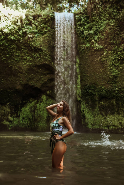 Beautiful sexy girl under a waterfall in Indonesia. - Фото, зображення