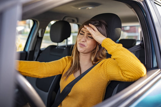 Nervous female driver sits at wheel, has worried expression as afraids to drive car by herself for first time. Frightened woman has car accident on road. People, driving, problems with transport - 写真・画像