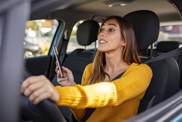 Texting and driving, behind the wheel. Breaking the law. Woman driving car distracted by her mobile phone. Woman typing message on the phone while waiting in the car. - Foto, Imagem