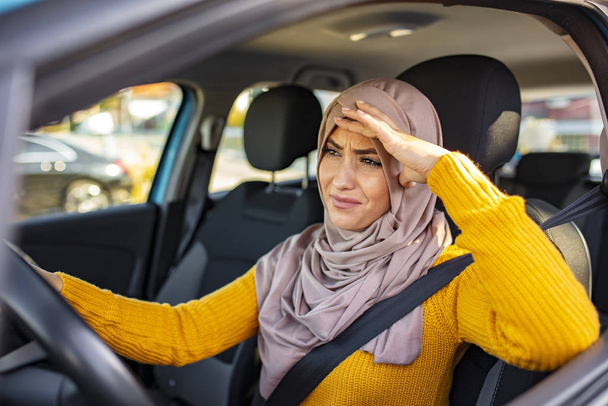 Stressed Muslim woman drive car feeling sad and angry. Distraught mid adult woman driving a car. Displeased young stressed angry pissed off woman driving car annoyed by heavy traffic - Foto, Imagem