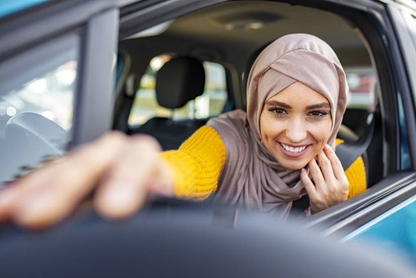 Modern Arabic woman adjusting a rear-view mirror. Middle Eastern Woman Driving a Car, Looking Forward. Beautiful caucasian Muslim Woman wearing light hijab in a car lifestyle shoot - Foto, Imagen