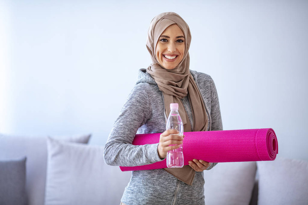 Muslim Woman getting ready for a workout. Young muslim woman ready to running. Refreshment after training.  Young sporty muslim woman athlete in sportswear drinkin - Photo, Image