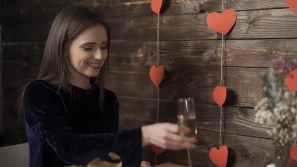 Mosolygós lány csörömpöl borosüveg és ajándékot cserél barátjával - Felvétel, videó