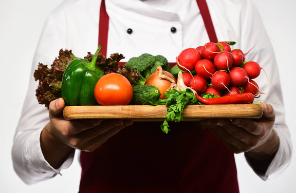 Szef kuchni trzyma deskę ze świeżymi warzywami. Koncepcja zdrowego żywienia. - Zdjęcie, obraz