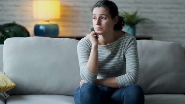 Video of depressed young woman thinking about her problems while sitting on the sofa at home. - Filmmaterial, Video