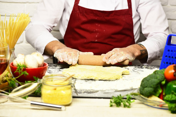 Italian cuisine concept. Male hands roll out dough - Photo, Image