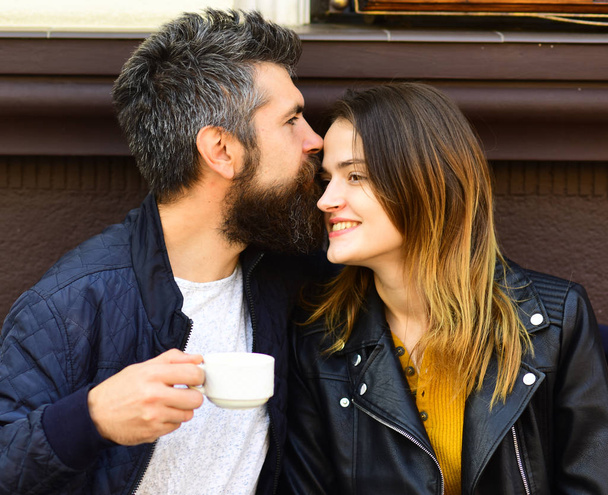 Girl and bearded guy have coffee on brown terrace background. - Foto, imagen