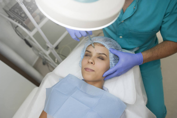 vista lateral del procedimiento de aumento de codo en una mujer joven realizado por un médico cosmetólogo con inyección de ácido hialurónico
. - Foto, imagen