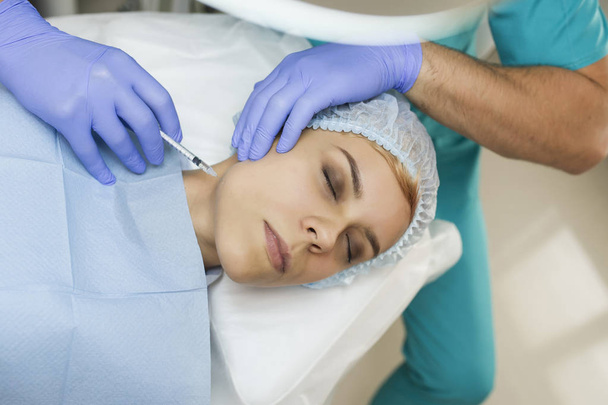 Vue du dessus de la procédure d'augmentation du menton sur une jeune femme faite par un médecin cosmétologue avec l'injection d'acide hyaluronique
. - Photo, image