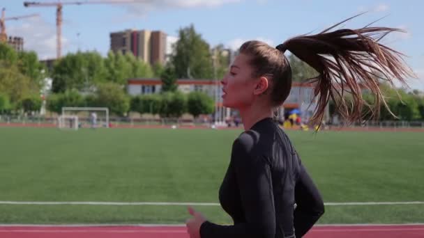 Slim woman running in city stadium - Кадры, видео