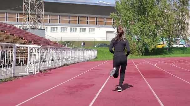 Mujer delgada corriendo en pista de carreras bajo el sol
 - Imágenes, Vídeo
