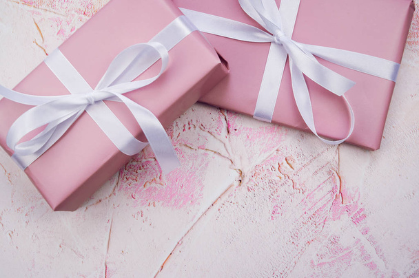 horizontal color photo of two pink presents with a white ribbon against light pink background with copy space - Foto, immagini