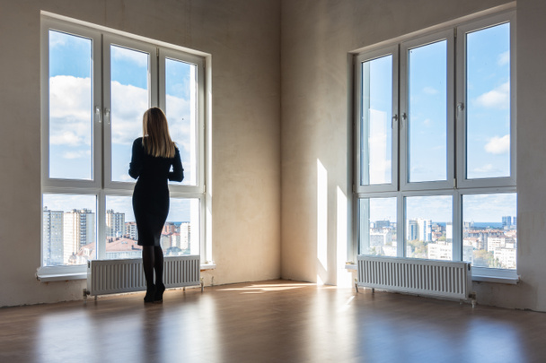 Une fille regarde dans les grands vitraux dans un appartement vide
 - Photo, image