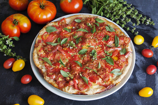 Pizza appetitosa con pomodori su sfondo scuro
 - Foto, immagini