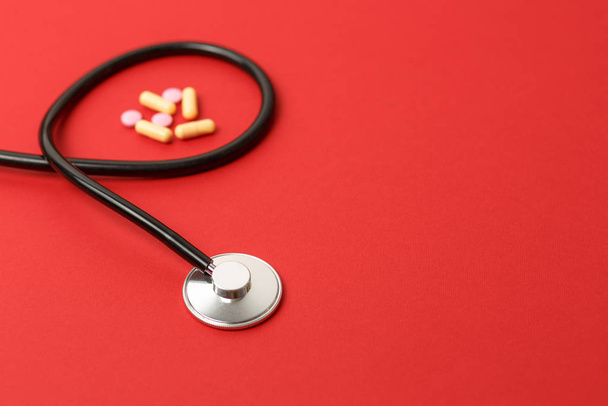 stethoscope on red background with pills - Photo, Image