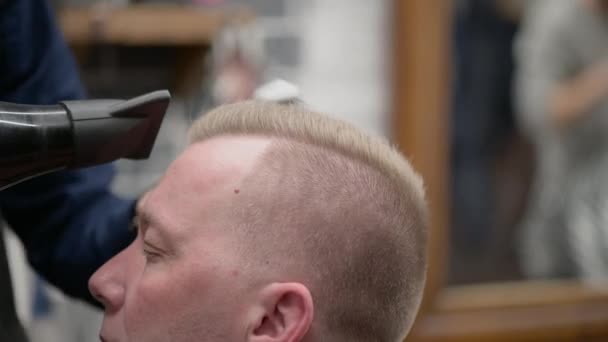 Чоловіча стрижка в перукарні. Крупним планом майстер відсікає чоловіка зі світлим волоссям з ножицями
 - Кадри, відео