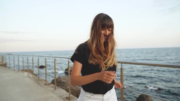 Jovem mulher adulta sorrindo, andando perto do mar
 - Filmagem, Vídeo