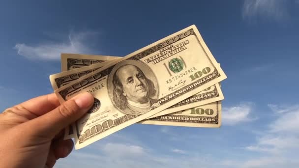 Girl holding money bill of 300 dollars on background of blue sky - Πλάνα, βίντεο