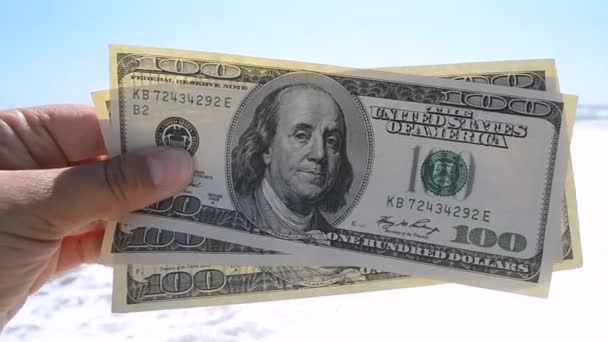Man holds three hundred dollar banknotes in his hands on a background - Materiał filmowy, wideo