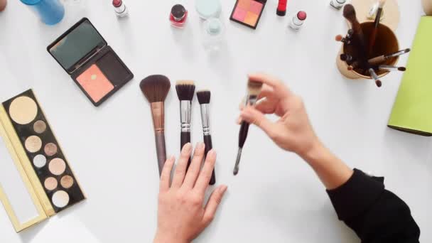 Vista superior de primer plano blogger belleza mostrando diferentes pinceles en el vídeo tutorial maquillaje
 - Metraje, vídeo