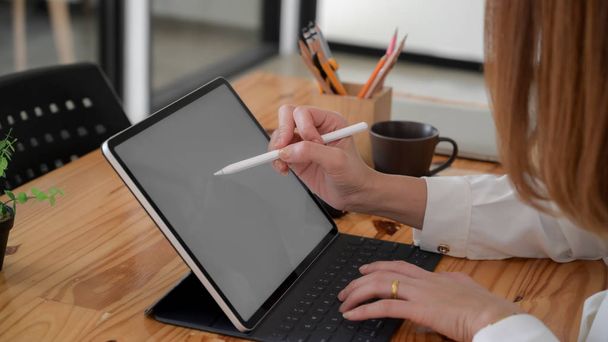 Vue latérale du dessin freelance féminin sur tablette écran vierge tout en étant assis dans un espace de travail simple co
 - Photo, image