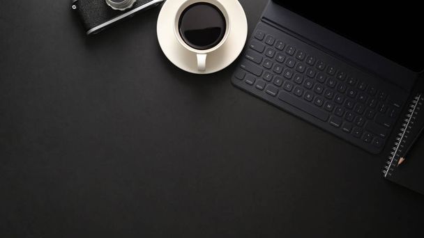 Widok z góry miejsca pracy z klawiaturą bezprzewodową, przestrzenią do kopiowania, kamerą i filiżanką kawy na czarnym stole  - Zdjęcie, obraz