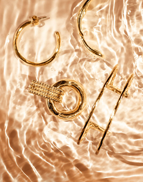 黄金のブレスレット、イヤリング、リング、ゴールドの水の上のジュエリー｜バックグラー - 写真・画像
