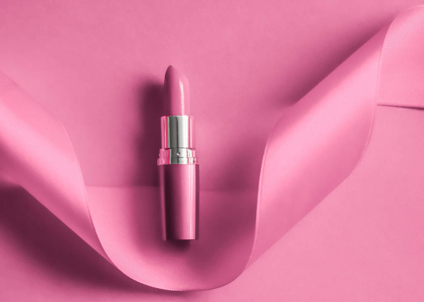 Luxe lippenstift en zijden lint op roze vakantie achtergrond, maken - Foto, afbeelding